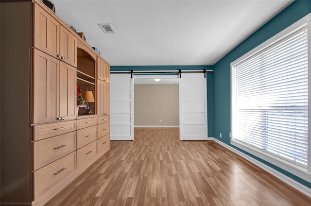 interior space with a barn door and light hardwood / wood-style flooring