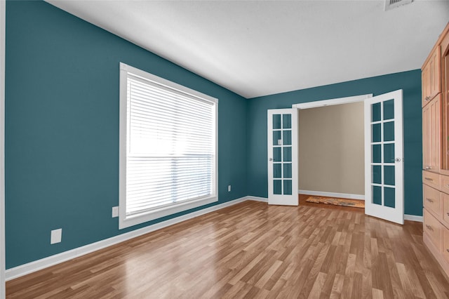 spare room featuring light wood-type flooring and french doors