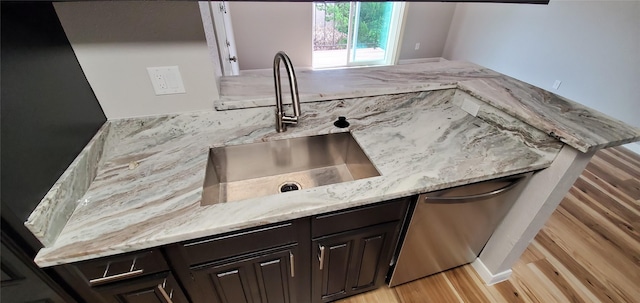 kitchen with sink, dark brown cabinets, light stone countertops, and dishwasher