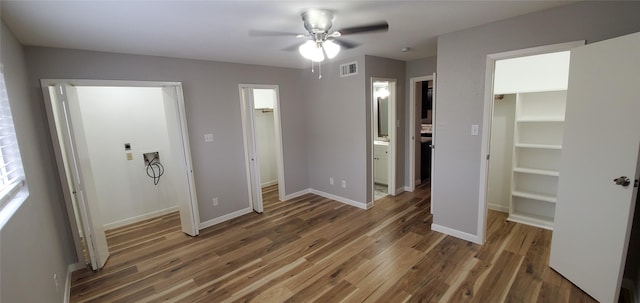 unfurnished bedroom featuring ceiling fan, ensuite bathroom, dark hardwood / wood-style floors, and a spacious closet