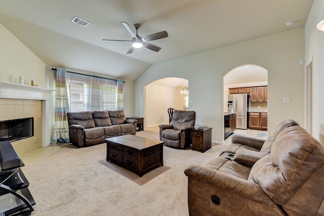 living room with a tile fireplace, vaulted ceiling, light carpet, and ceiling fan