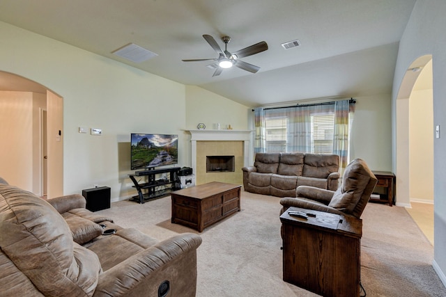 living room with ceiling fan, light colored carpet, lofted ceiling, and a tile fireplace