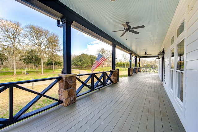 wooden deck featuring a porch, a yard, and ceiling fan