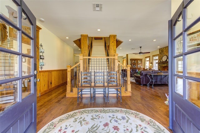 entrance foyer with dark wood-type flooring, ceiling fan, and wood walls