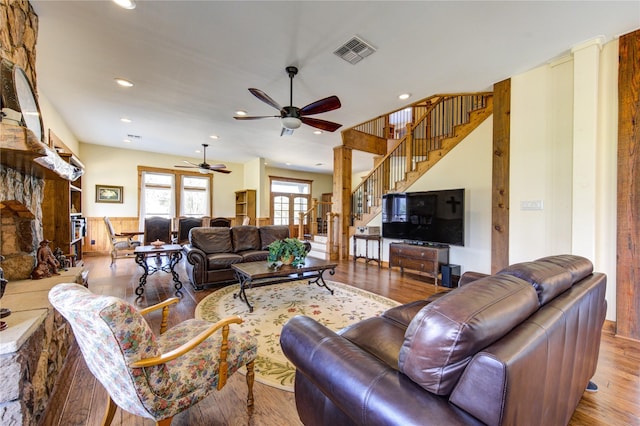 living room with a stone fireplace, light hardwood / wood-style floors, and ceiling fan