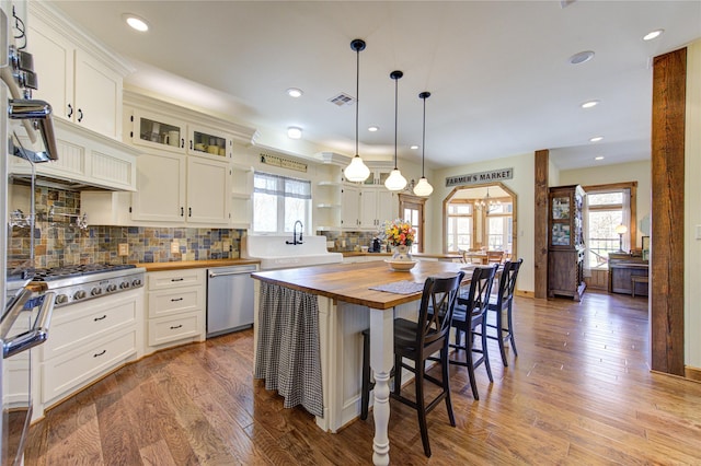 kitchen featuring appliances with stainless steel finishes, a center island, butcher block countertops, and white cabinets