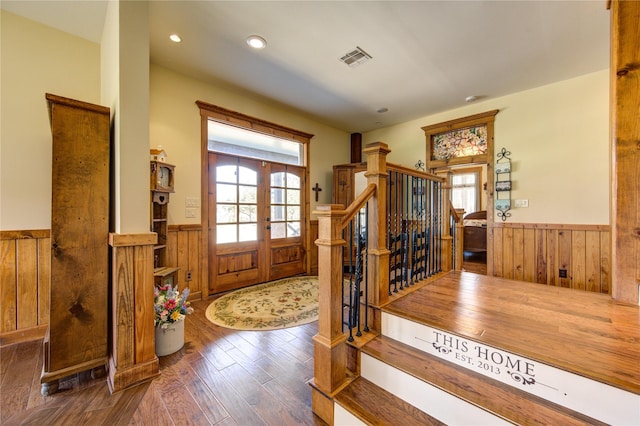 entryway featuring a healthy amount of sunlight, wooden walls, dark hardwood / wood-style flooring, and french doors