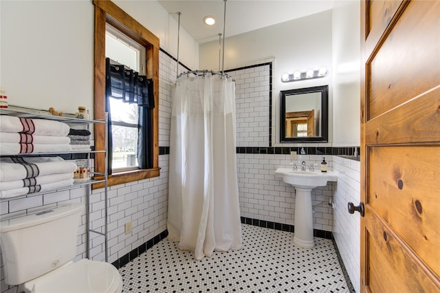 bathroom with a shower with curtain, tile patterned floors, toilet, and tile walls