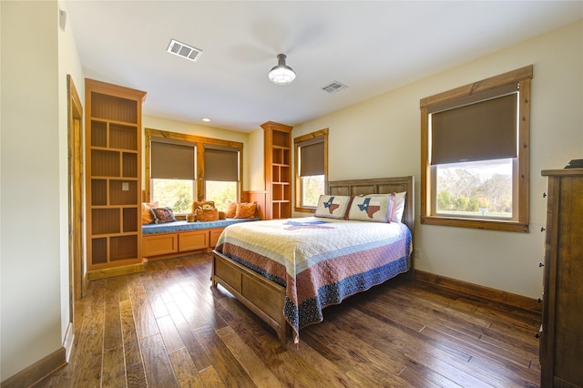 bedroom with multiple windows and dark hardwood / wood-style floors