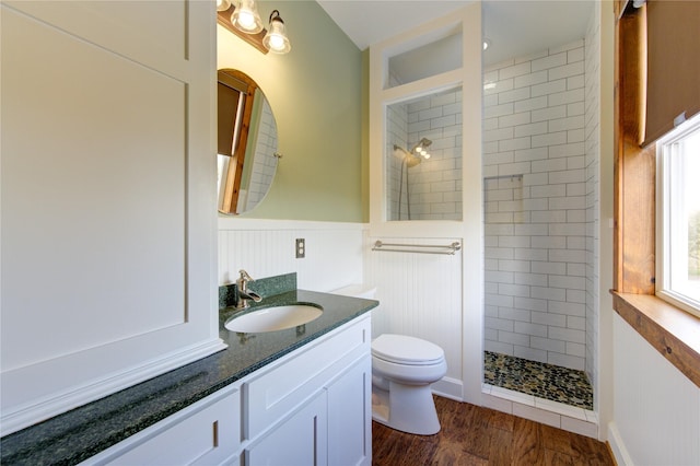 bathroom featuring hardwood / wood-style flooring, vanity, toilet, and a tile shower