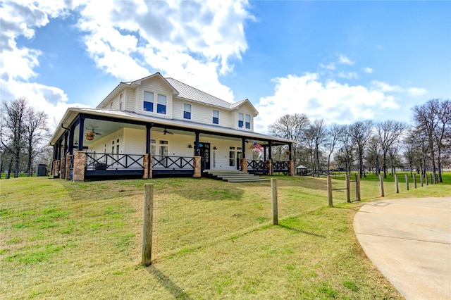 farmhouse inspired home with a front yard, ceiling fan, and covered porch