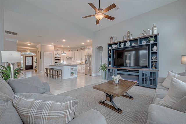 living area featuring arched walkways, visible vents, baseboards, and light tile patterned floors