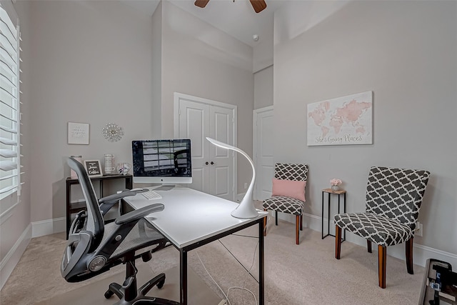 home office with light carpet, a towering ceiling, and baseboards