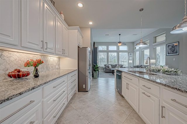 kitchen featuring hanging light fixtures, appliances with stainless steel finishes, white cabinetry, and a sink