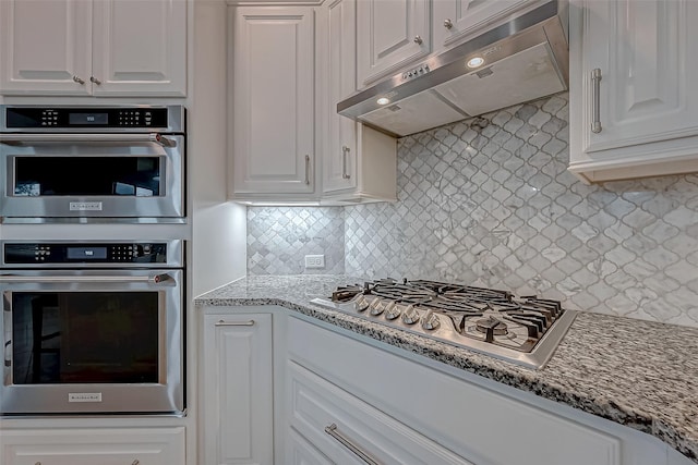 kitchen featuring light stone counters, appliances with stainless steel finishes, white cabinetry, and under cabinet range hood