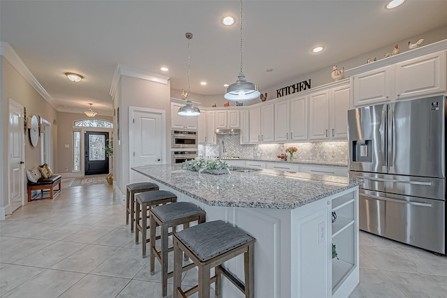 kitchen with a kitchen island with sink, stainless steel appliances, light stone countertops, and white cabinets