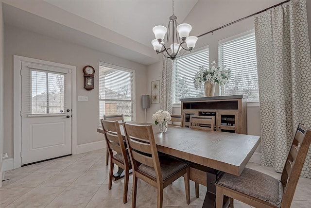 dining space with a notable chandelier, vaulted ceiling, baseboards, and light tile patterned floors