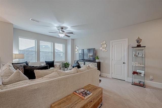 living area featuring baseboards, a ceiling fan, visible vents, and light colored carpet