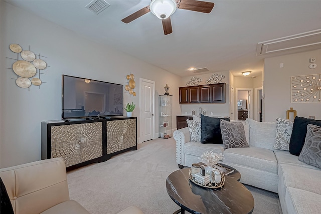 living room with attic access, light colored carpet, visible vents, and a ceiling fan