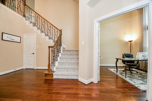 stairs featuring a towering ceiling and hardwood / wood-style floors