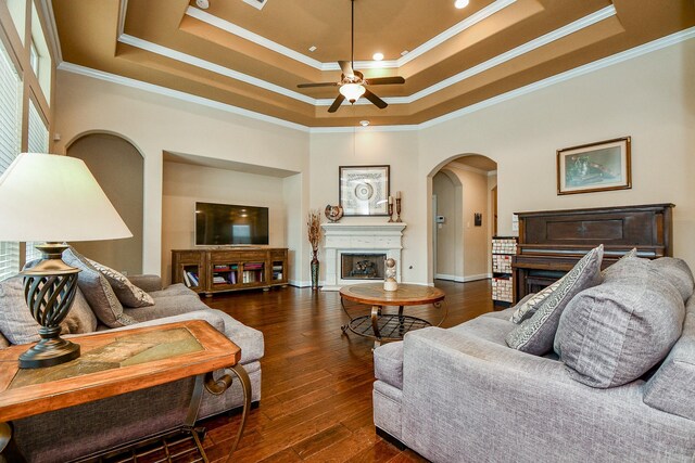 living room with crown molding, ceiling fan, dark hardwood / wood-style flooring, and a raised ceiling