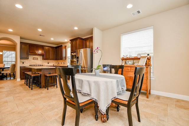 dining area with arched walkways, visible vents, recessed lighting, and baseboards