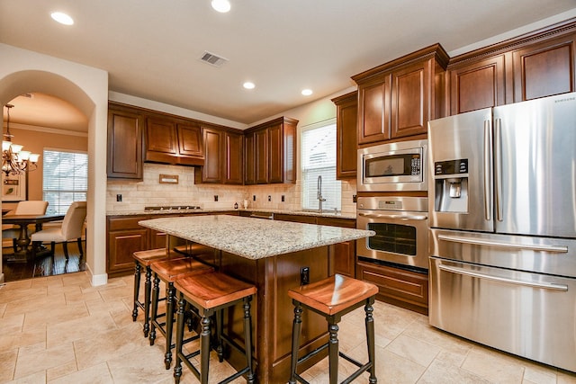 kitchen featuring visible vents, a sink, tasteful backsplash, stainless steel appliances, and arched walkways