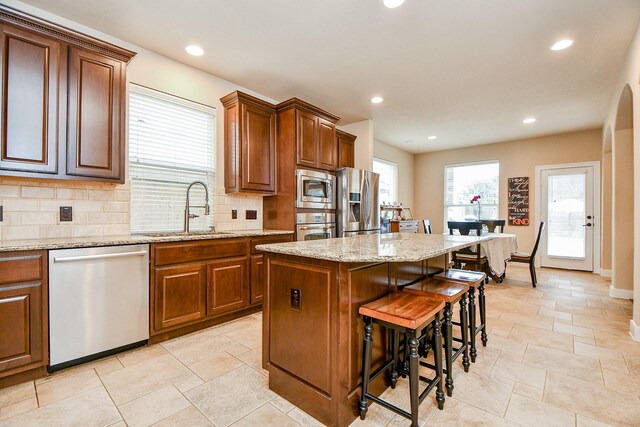 kitchen with sink, a kitchen island, stainless steel appliances, tasteful backsplash, and a kitchen bar