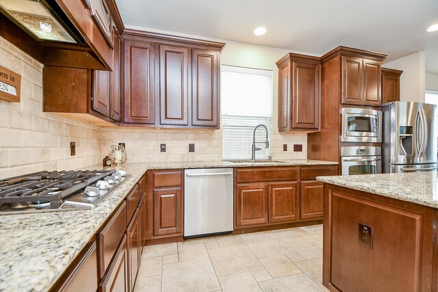 kitchen with appliances with stainless steel finishes, tasteful backsplash, sink, light stone counters, and custom range hood