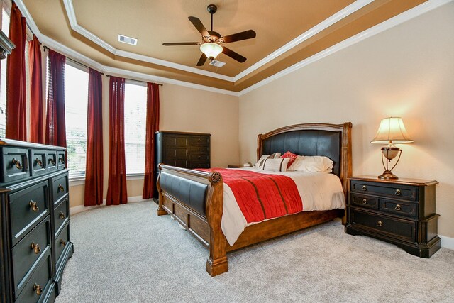 bedroom with ornamental molding, light carpet, ceiling fan, and a tray ceiling