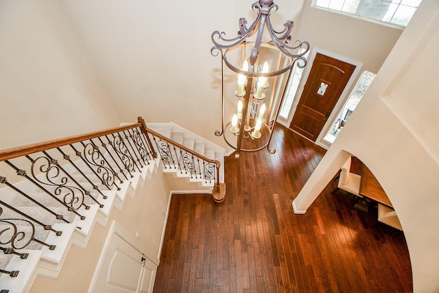 entrance foyer featuring stairway, a high ceiling, an inviting chandelier, and dark wood finished floors