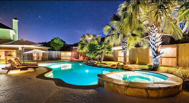 pool at twilight featuring a patio, a pool with connected hot tub, and a fenced backyard