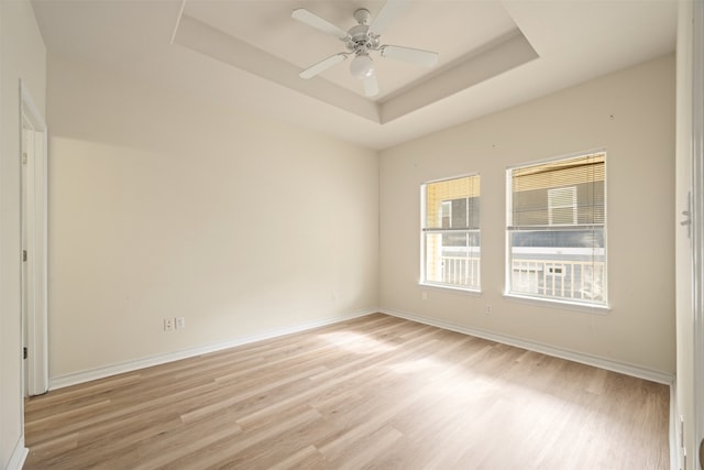 spare room featuring a tray ceiling, light hardwood / wood-style floors, and ceiling fan