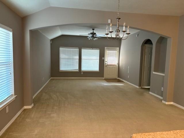 unfurnished dining area with vaulted ceiling, plenty of natural light, carpet floors, and ceiling fan with notable chandelier