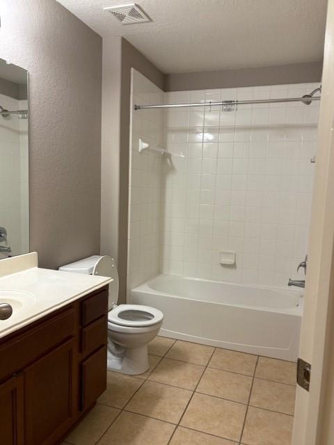 full bathroom with tile patterned floors, toilet, tiled shower / bath, a textured ceiling, and vanity