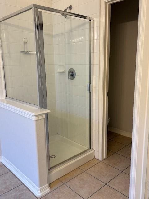 bathroom featuring tile patterned flooring, toilet, and a shower with shower door