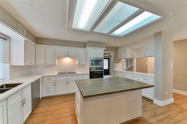 kitchen featuring white cabinetry, wooden counters, a center island, light hardwood / wood-style flooring, and stainless steel appliances