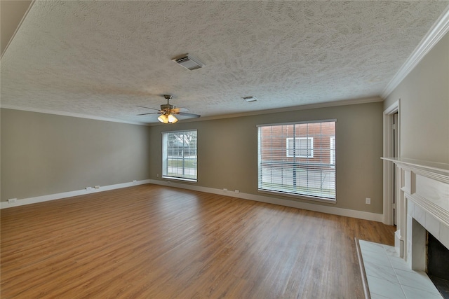 unfurnished living room featuring light hardwood / wood-style flooring, a tile fireplace, ceiling fan, ornamental molding, and a textured ceiling