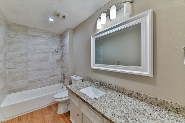 full bathroom featuring lofted ceiling, toilet, tiled shower / bath, vanity, and hardwood / wood-style floors