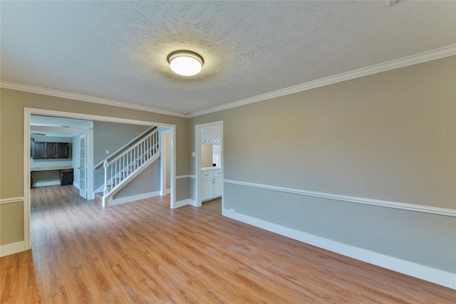 unfurnished room featuring crown molding, a textured ceiling, and light wood-type flooring