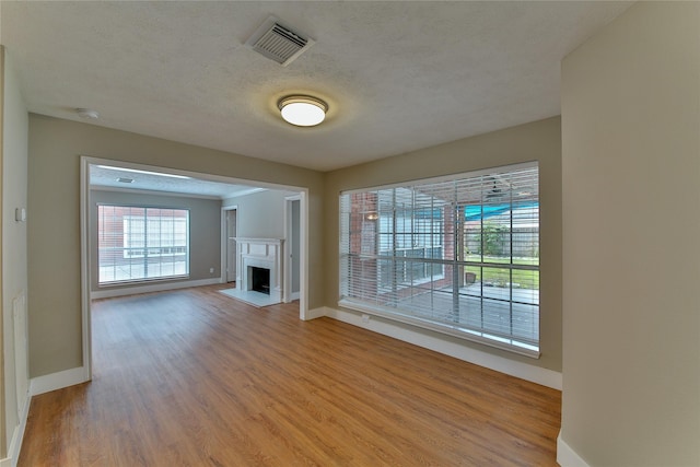 unfurnished living room with a healthy amount of sunlight, wood-type flooring, and a textured ceiling