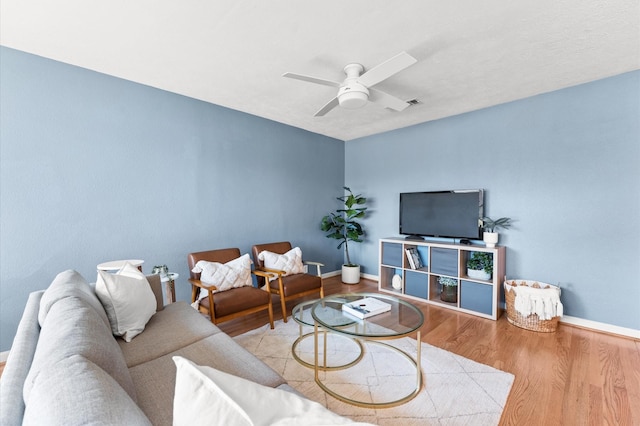 living room featuring baseboards, a ceiling fan, and wood finished floors