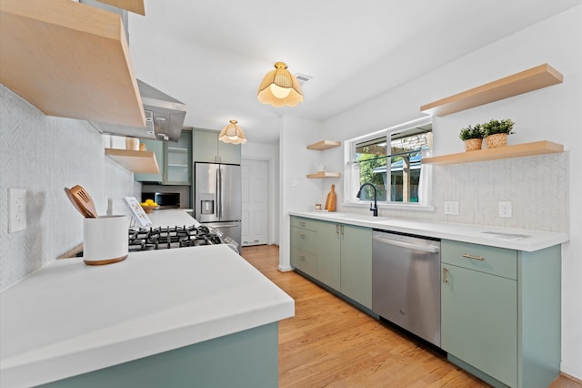 kitchen featuring a sink, appliances with stainless steel finishes, green cabinets, and open shelves