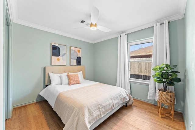 bedroom featuring wood finished floors, visible vents, and ornamental molding