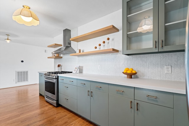 kitchen featuring open shelves, wall chimney range hood, visible vents, and stainless steel gas range