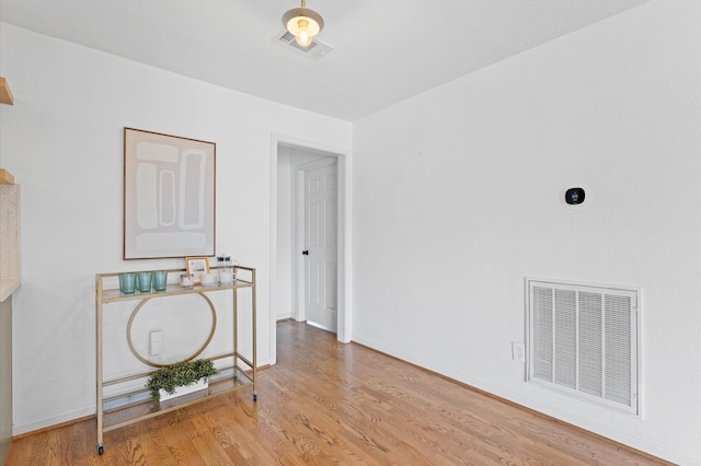 empty room featuring visible vents, baseboards, and wood finished floors