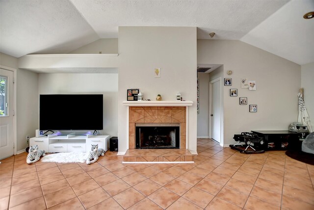 tiled living room with lofted ceiling, a textured ceiling, and a fireplace