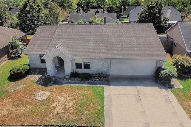 view of front facade featuring concrete driveway, a shingled roof, a front lawn, and an attached garage