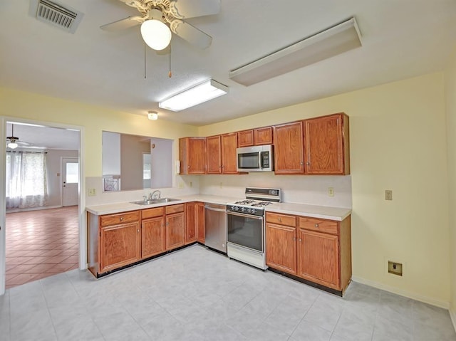 kitchen featuring stainless steel appliances, light countertops, brown cabinetry, and visible vents