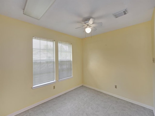 empty room with light tile patterned floors, ceiling fan, visible vents, and baseboards